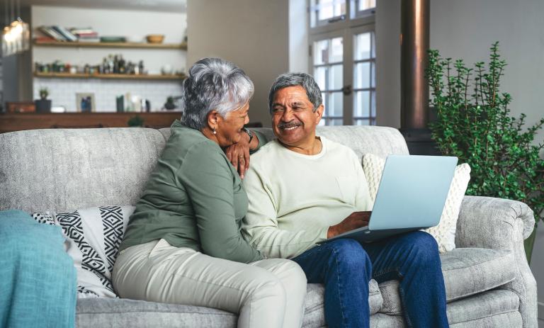 a senior couple using a laptop on the sofa at home