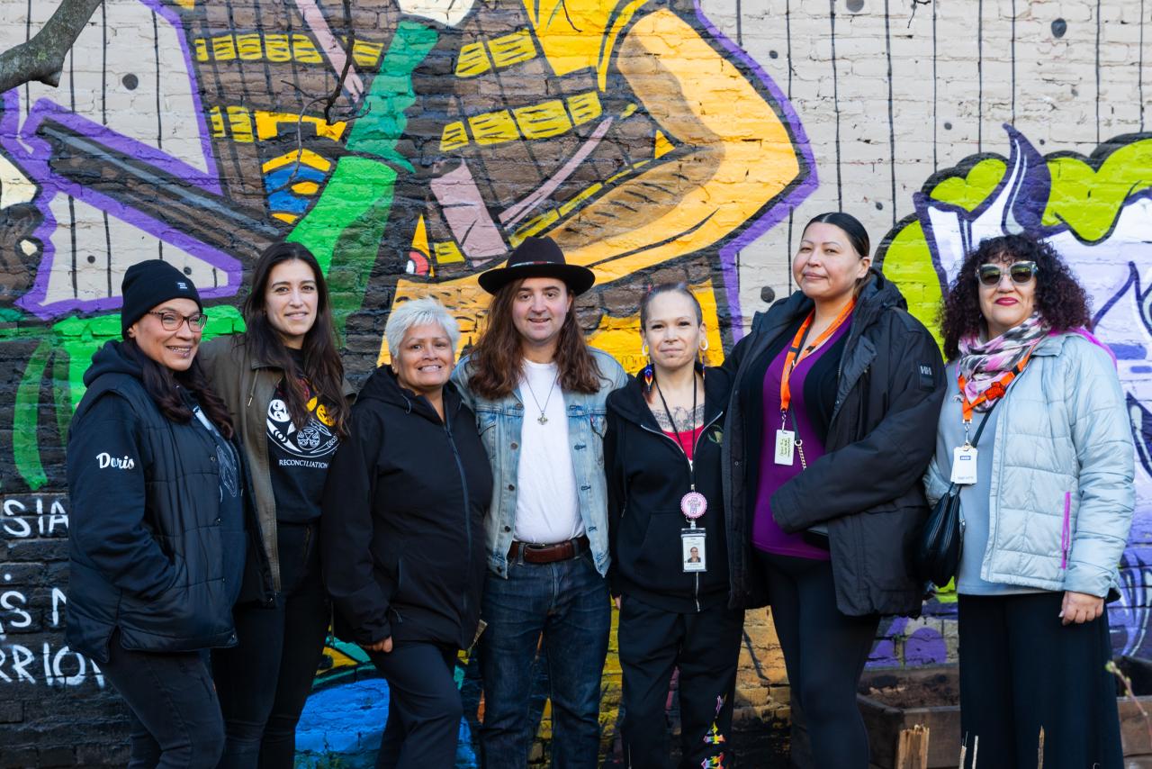 Members of the Indigenous Health Outreach team posing in front of a wall with art