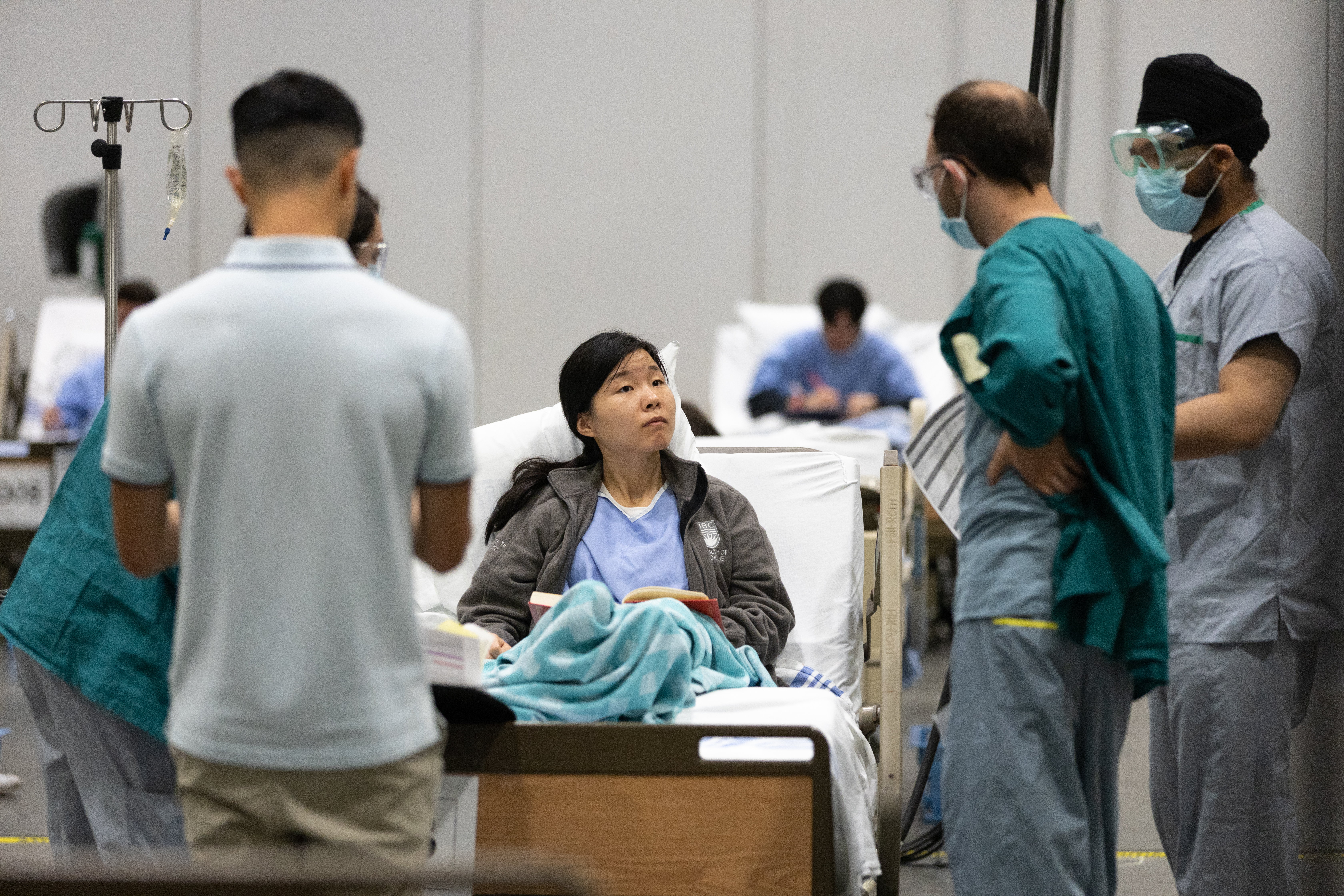 Doctors and nurses standing around student in patient simulation 