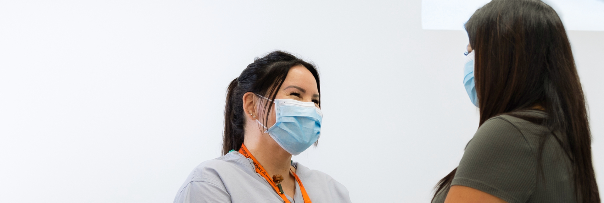 A nurse talking to a patient while wearing a mask