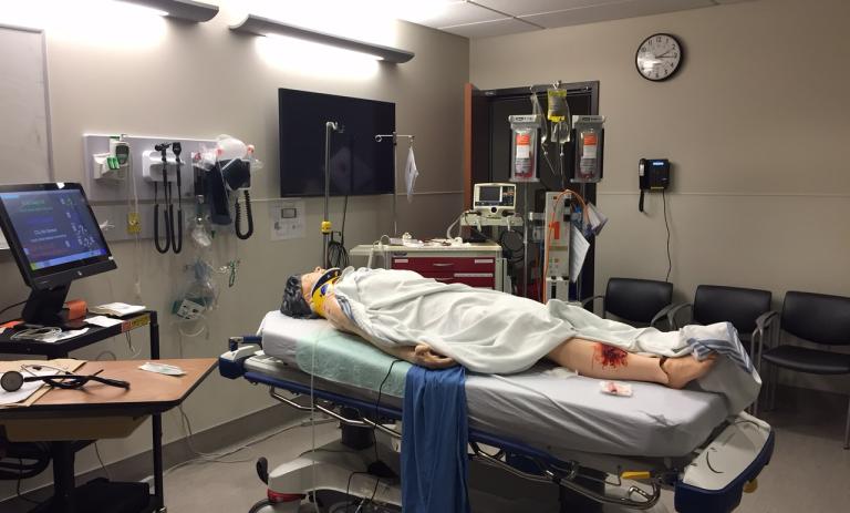 Manequin lying on a hospital bed in a Coastal Simulation Program.