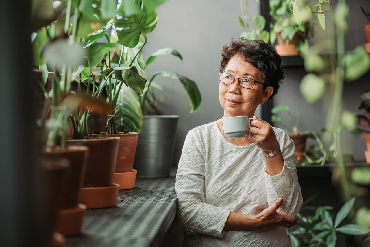 Senior woman sitting peacefully in an indoor garden.