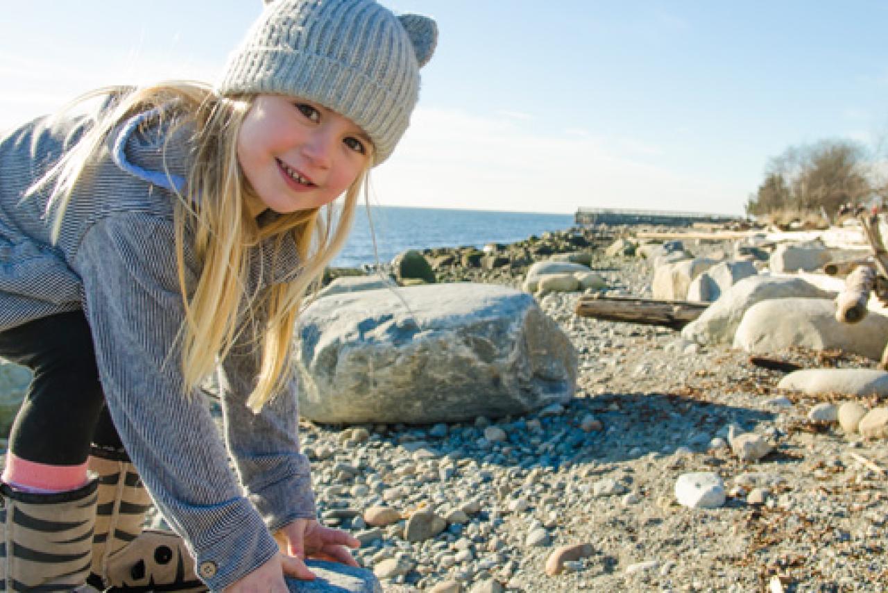 Photo of a child picking up rocks on a beach.