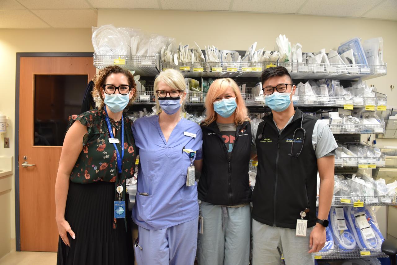 Four Vancouver Coastal Health employees wearing masks posing for a photo in a hospital.