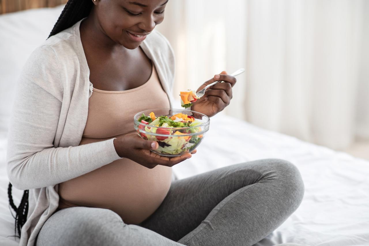 Happy pregnant person holding a bowl of fresh salad