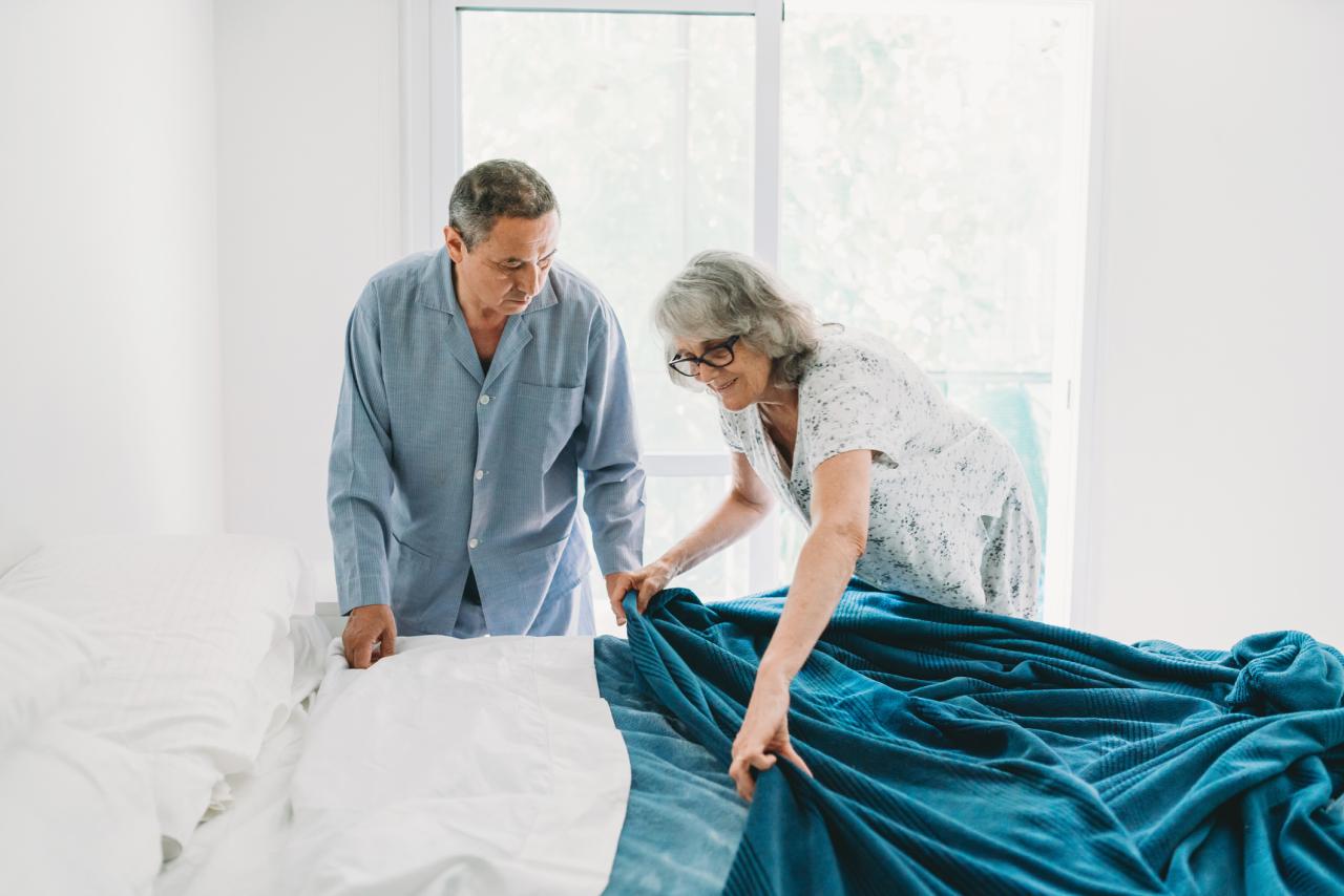 Mature couple making the bed together