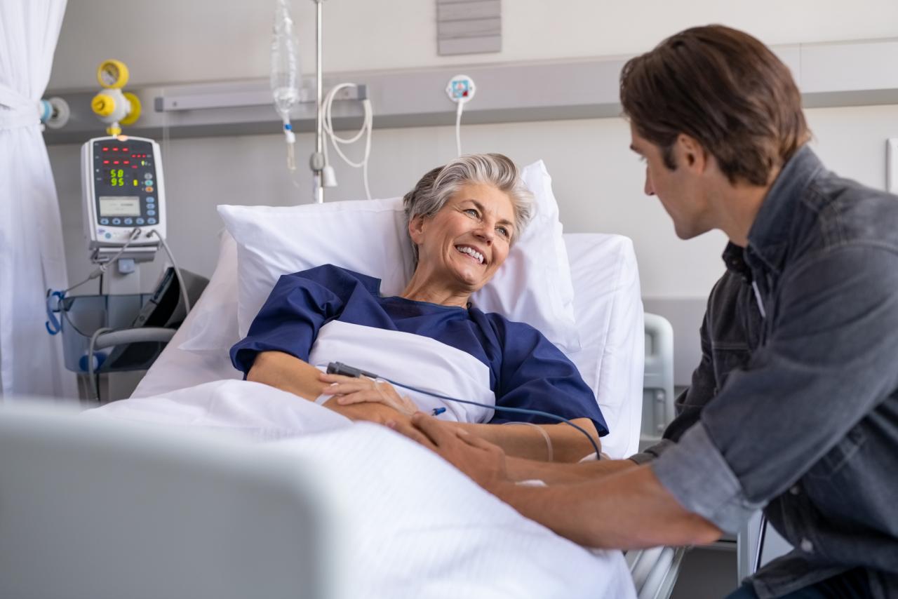 Patient talking with a visitor while laying in a hospital bed