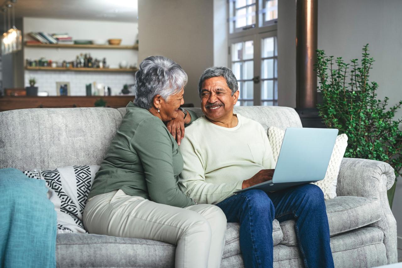 a senior couple using a laptop on the sofa at home