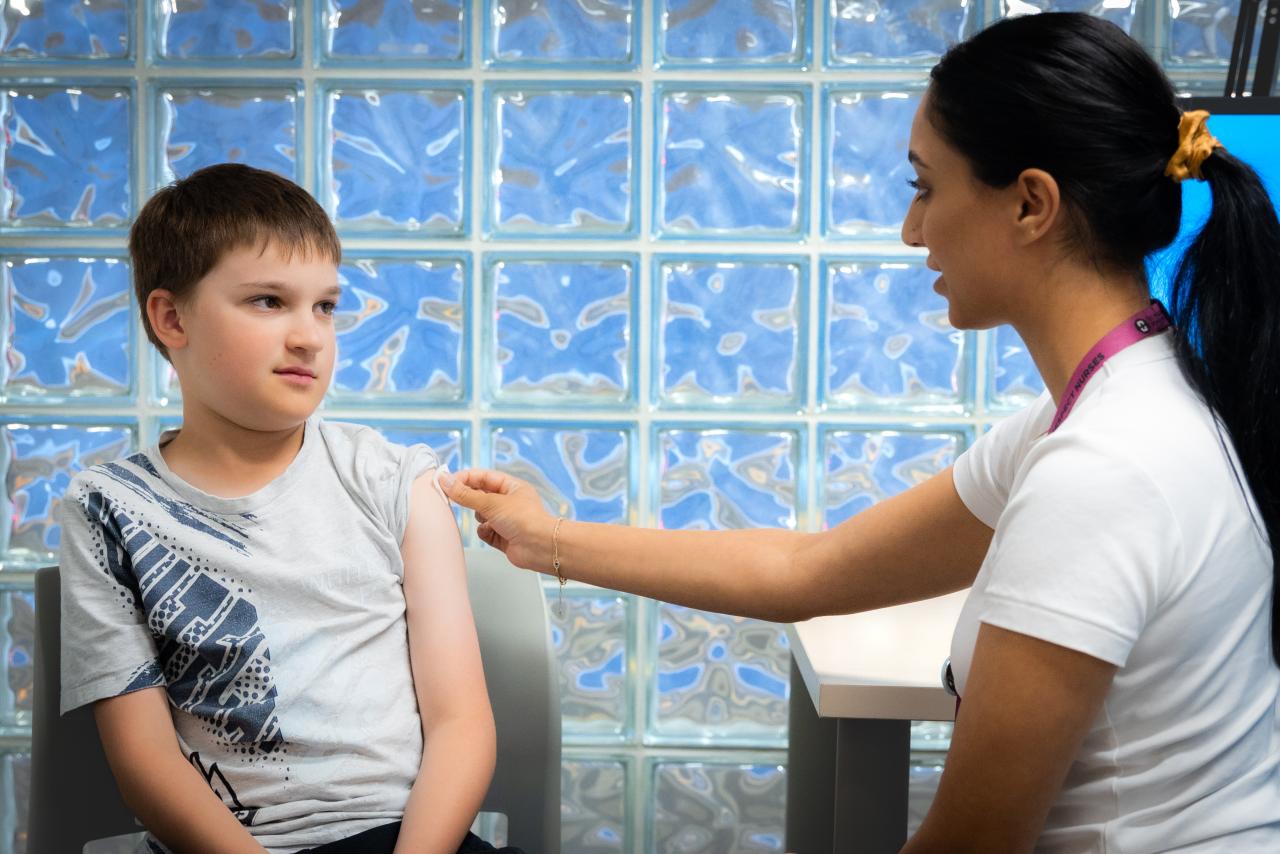 Young person sitting with VCH staff member for their immunizations.