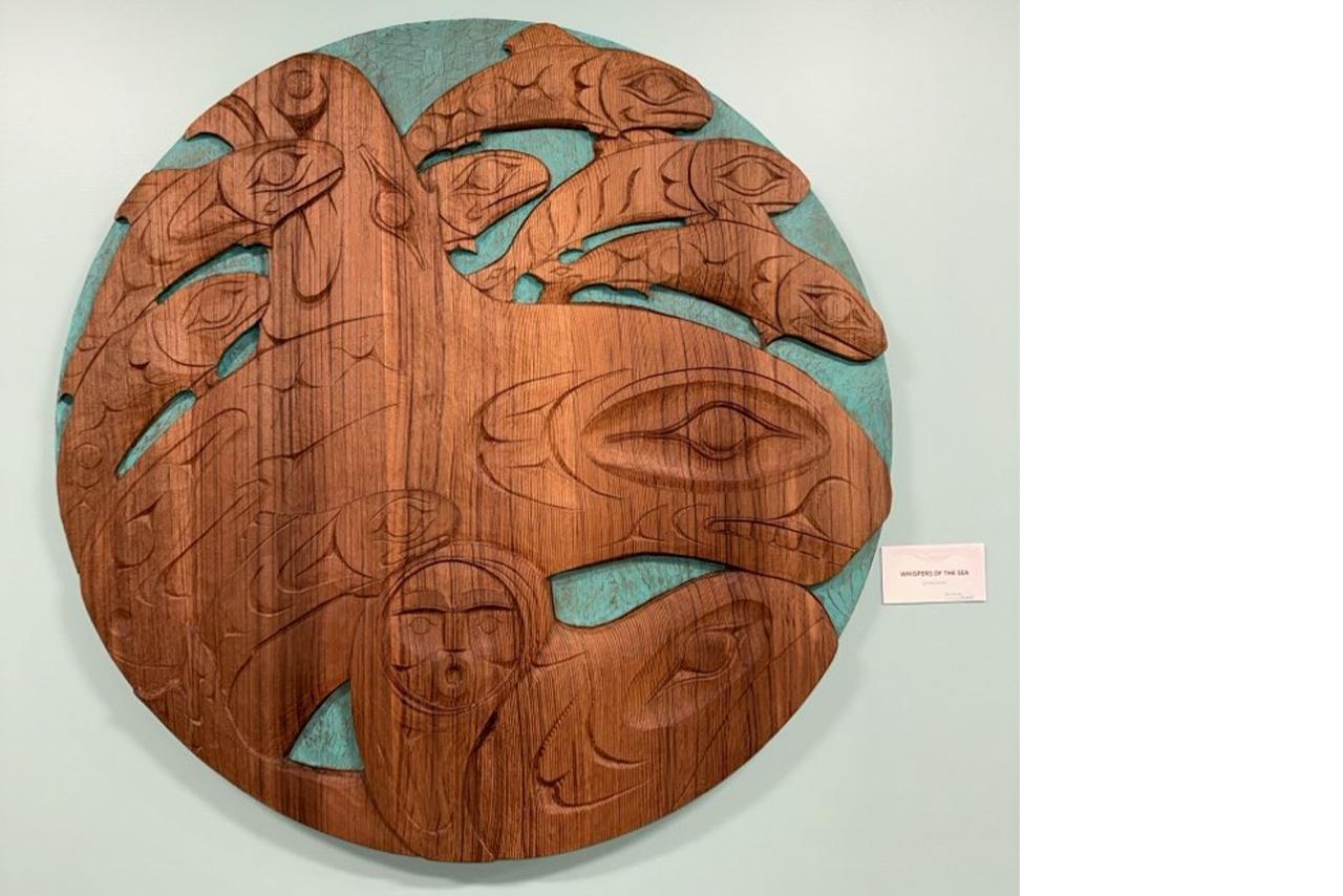 Indigenous wooden carving mounted on a white wall 