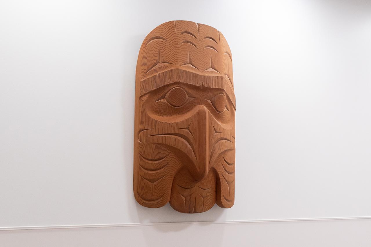 Indigenous wooden carving mounted on a white wall 