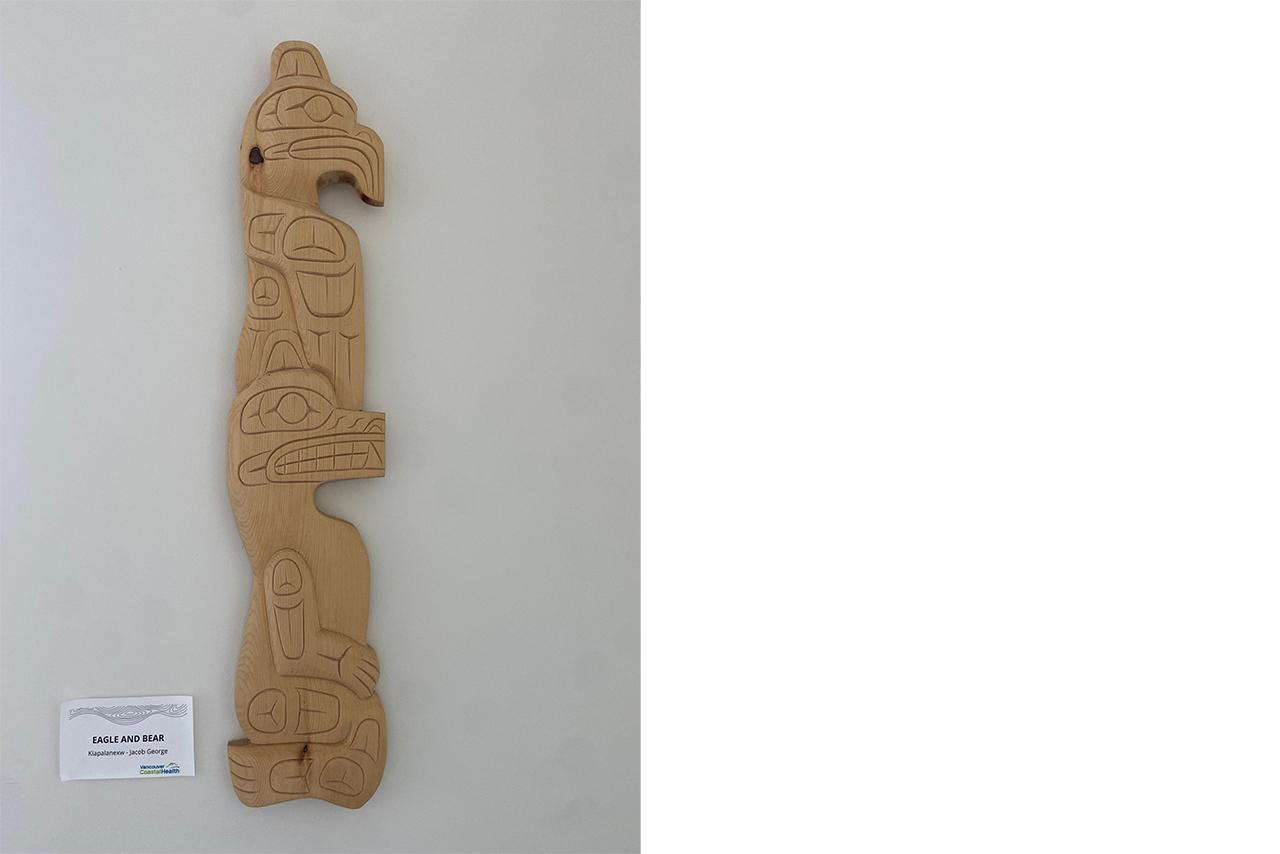 Indigenous wooden carving mounted on a white wall 