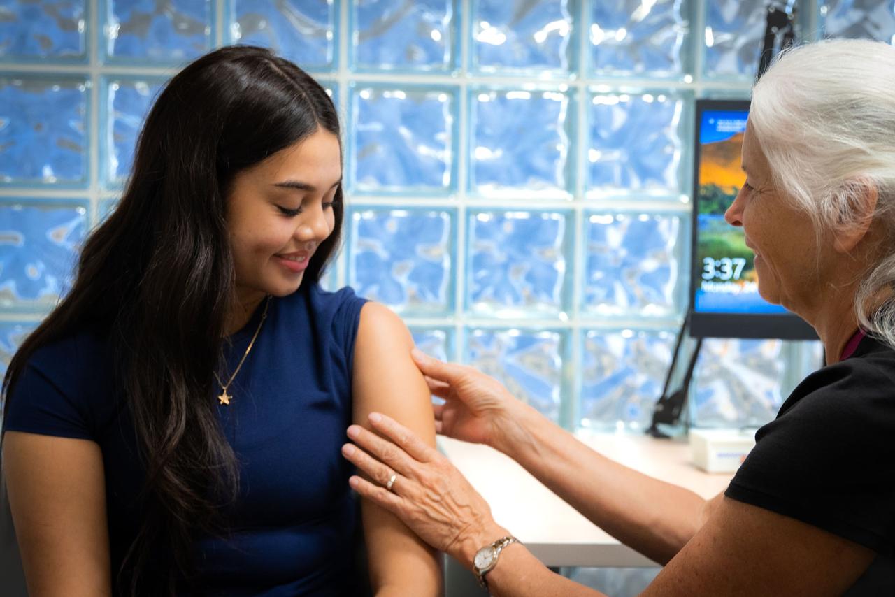 Younger woman getting vaccine from older healthcare worker in a welcoming medical room