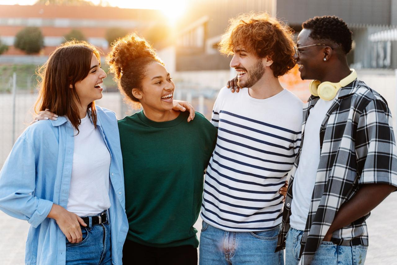group of two girls and two guys standing looking and smiling at each other in an outdoor plaza