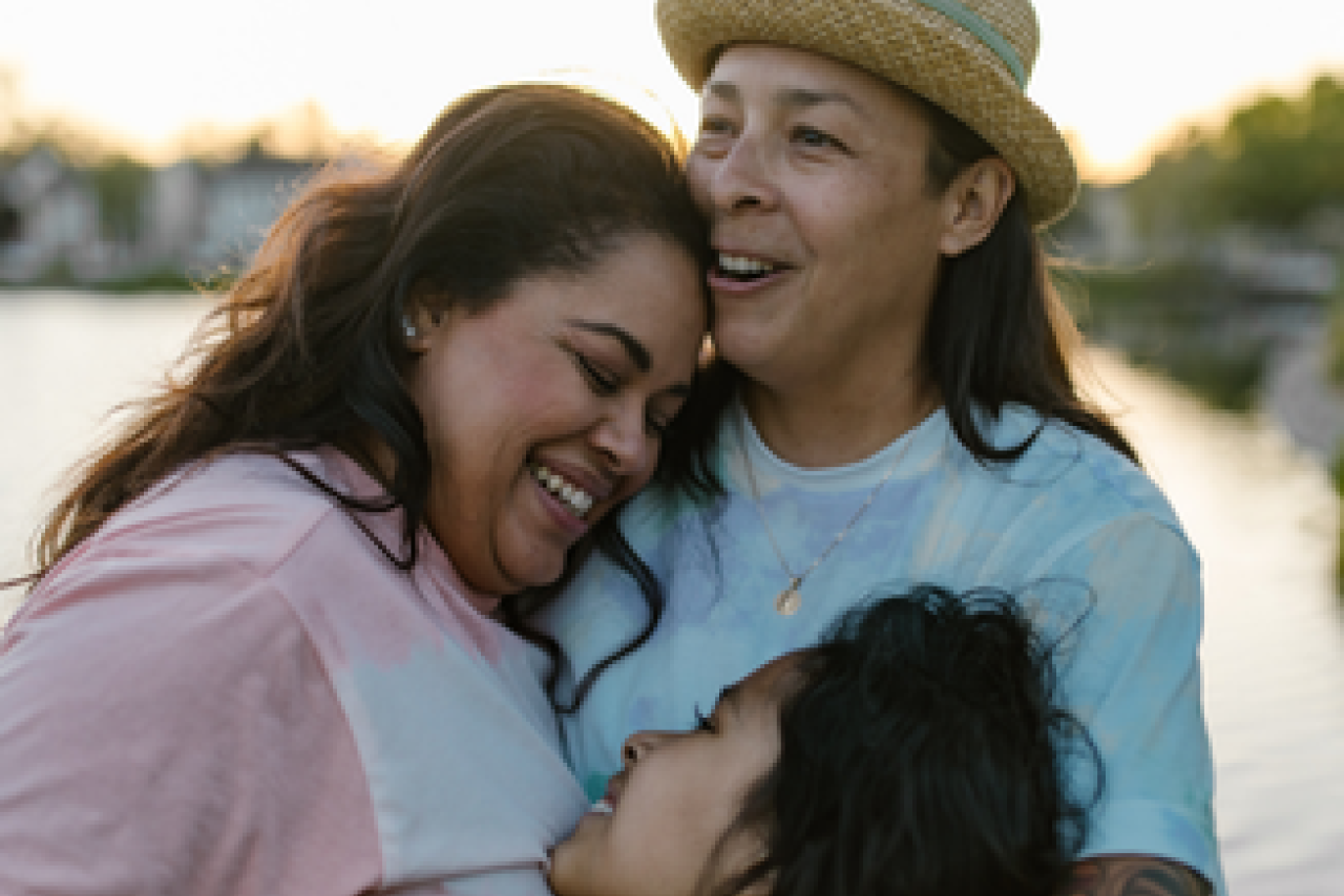 Family of three with hugging all together with smiles on their faces.