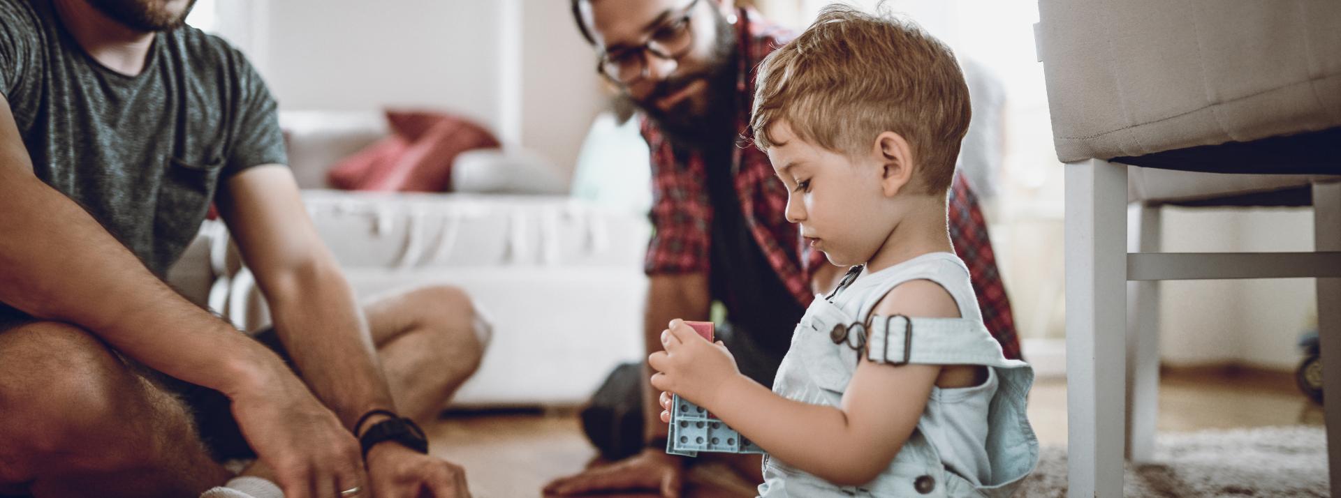 A toddler and their parents playing with toys on the ground.