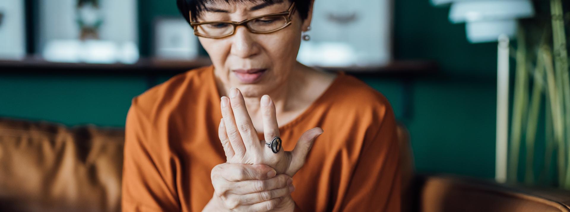 woman rubbing her hands in discomfort, suffering from arthritis