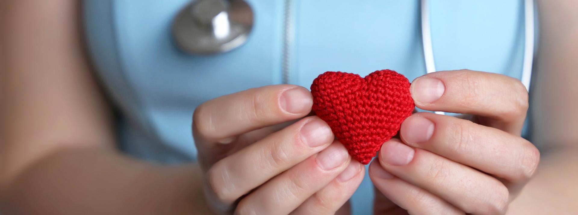 doctor holding red knitted heart in hands