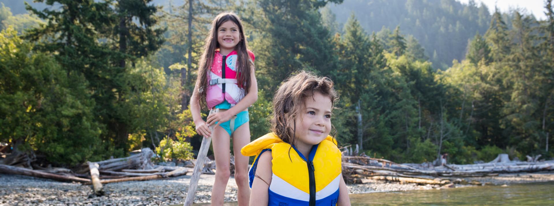 Two girls playing on driftwood in the sea
