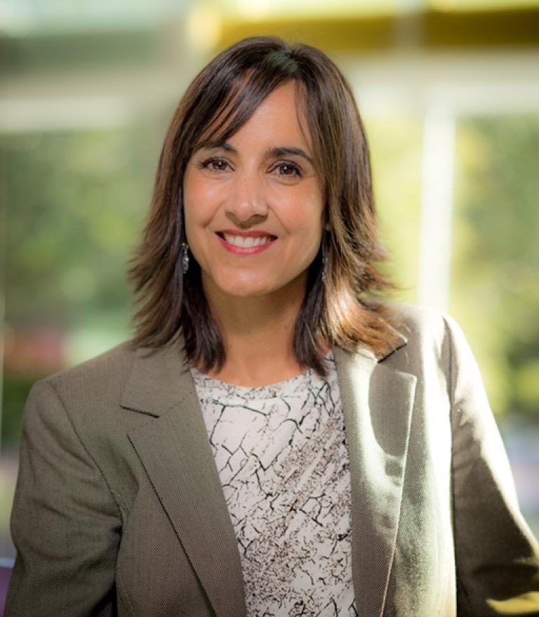 A portrait of Darcia Pope indoors.  She is wearing a white shirt and grey blazer