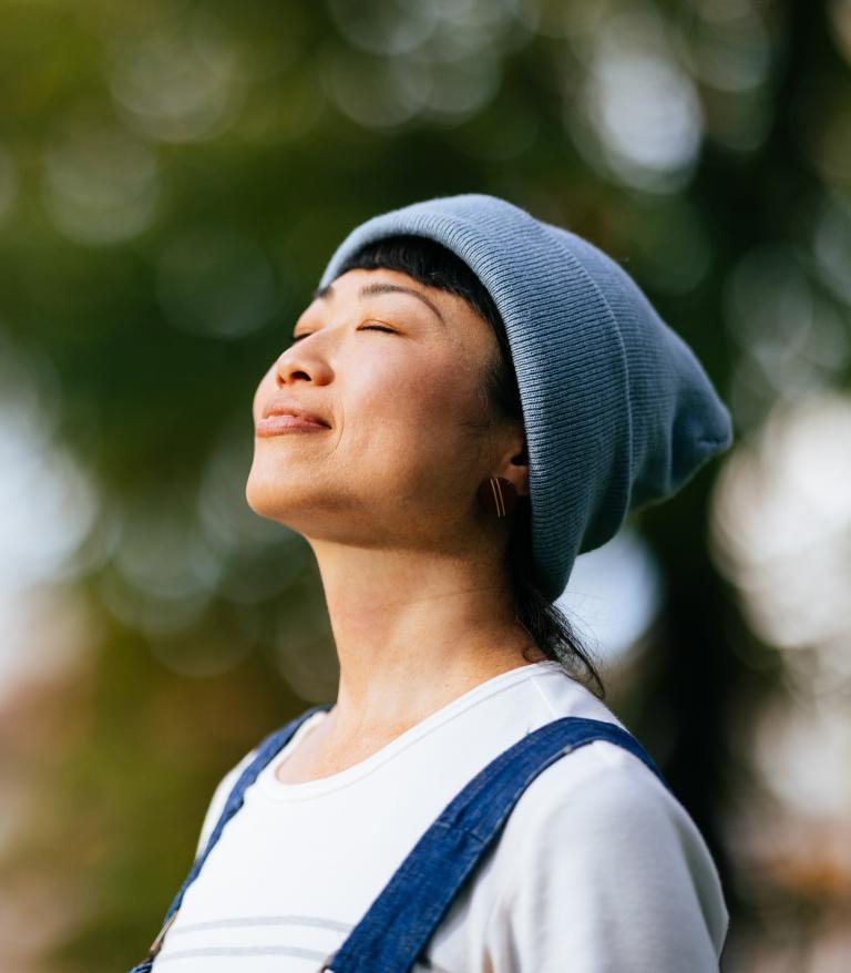 A person taking a deep breath while outside on a sunny day