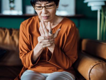 woman rubbing her hands in discomfort, suffering from arthritis