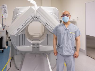staff stands beside CT machine