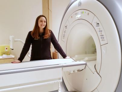 Rebecca Weiss standing behind an MRI machine.
