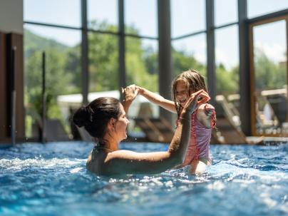 An adult and child play in a hotel pool