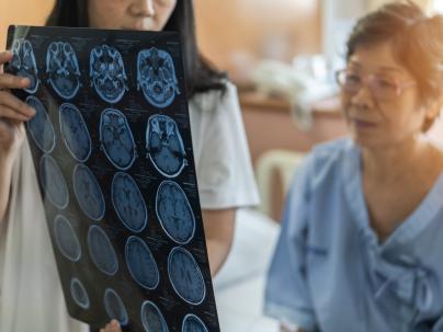 A doctor reviews a CT scan image with a patient in a hospital