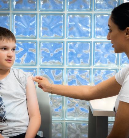 Young person sitting with VCH staff member for their immunizations.